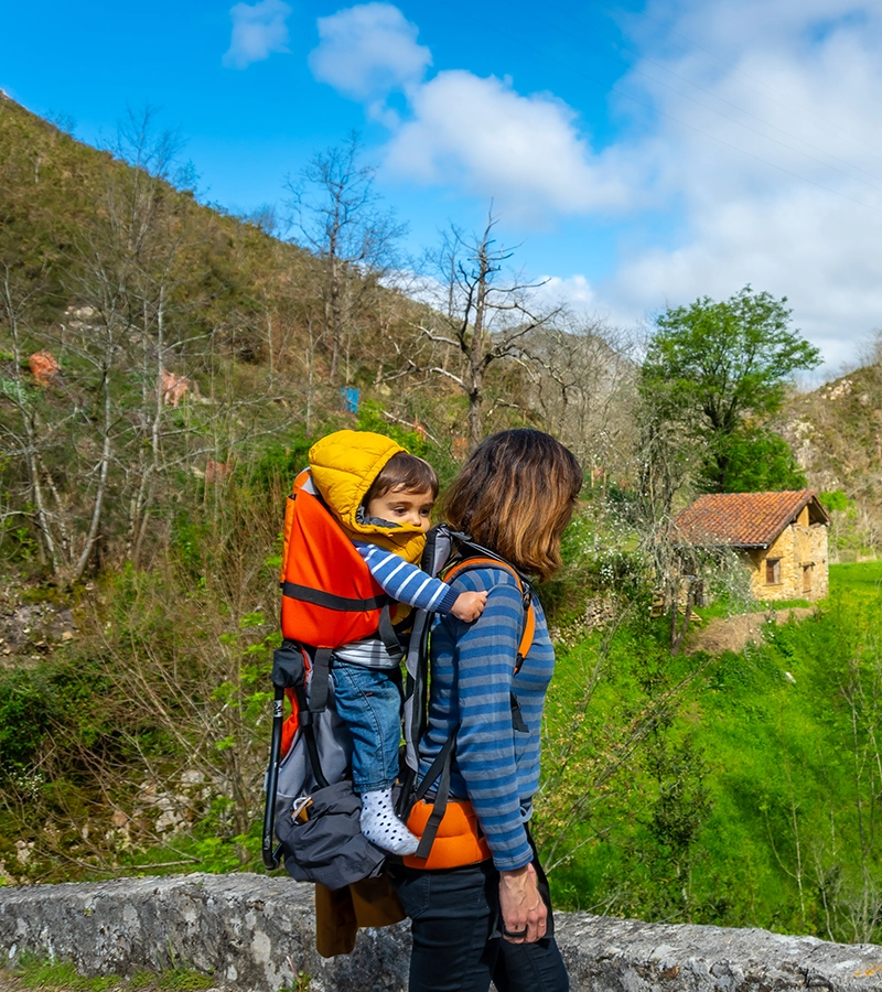 Madre con niño en la espalda haciendo el camino.